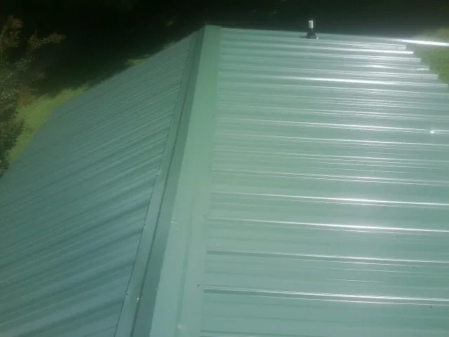 New green metal panels meeting at the ridge of a roof — Flat Roof Repair work by our crew in Cold Spring