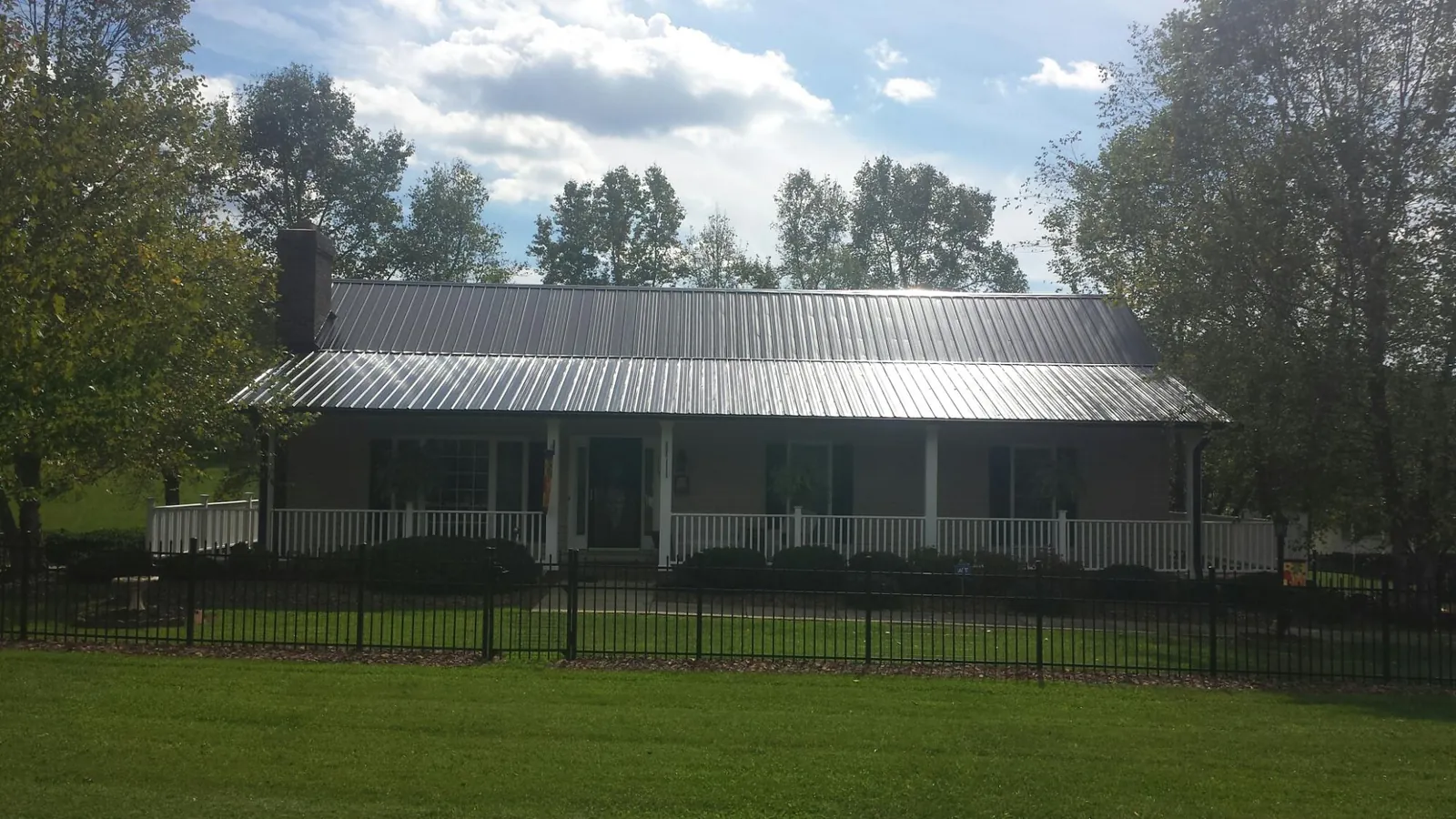 Gray metal roof on a brick ranch with a full width front porch — Gutter Guard Installation work by our crew in Cold Spring