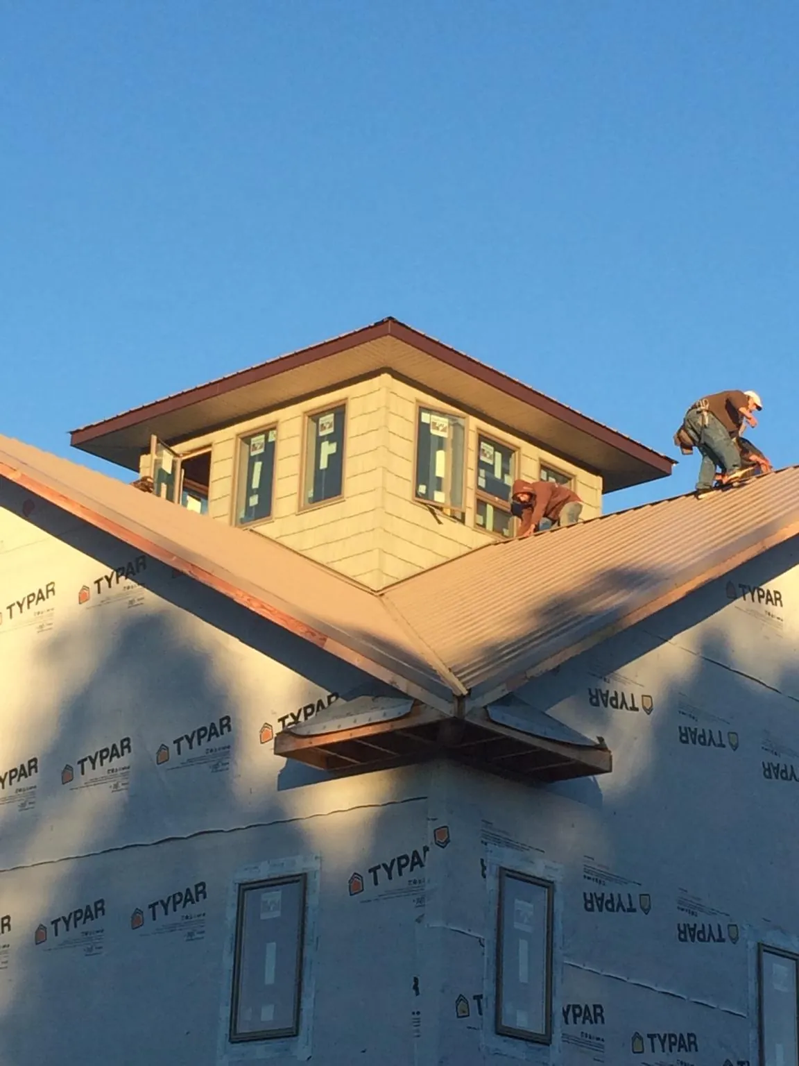 Roofers working around a rooftop cupola on a new metal roof at sunset — Roof Waterproofing in Cold Spring by Roofing Brothers